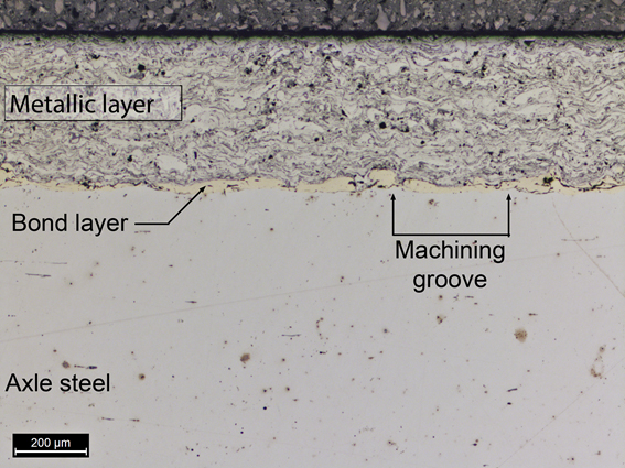 Metallurgical cross-section showing the applied surface layers and the steel substrate from the axle
